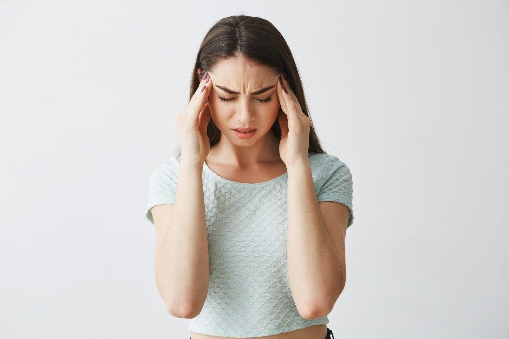 4 señales que no debemos ignorar: Cerebro en alerta: migraña, sueño, memoria y ACV. 2 young beautiful brunette girl frowning touching temples headache isolated white background