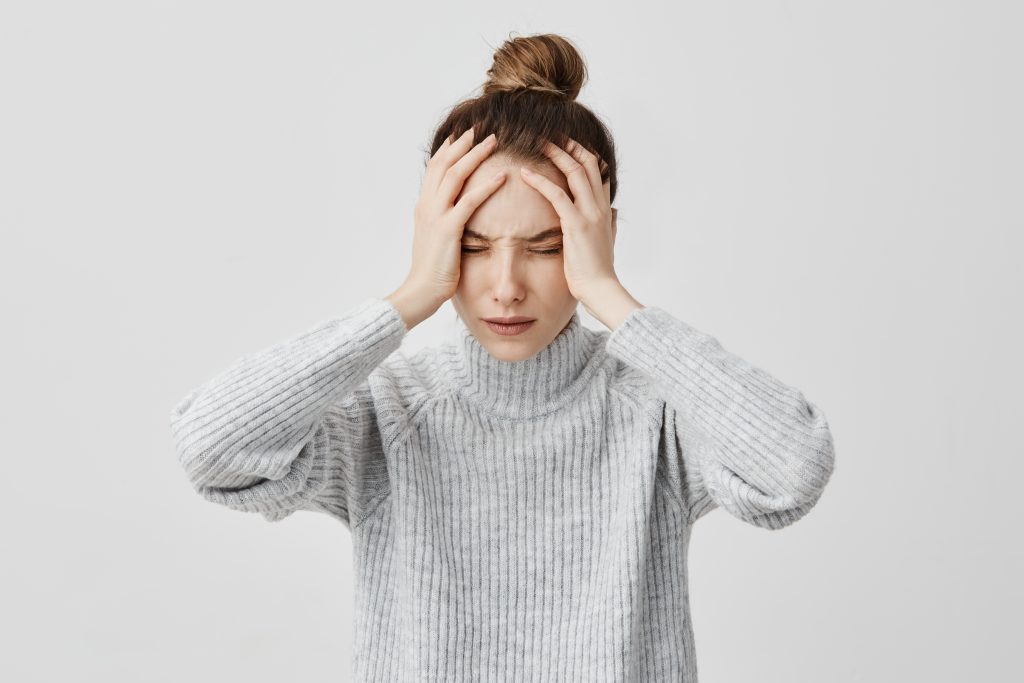 Entre melodías y emociones: ¿cómo influyen la música y la ansiedad materna en el bebé? 4 exhausted young woman touching her head with eyes closed female exchange worker suffering from unbearable headache health concept