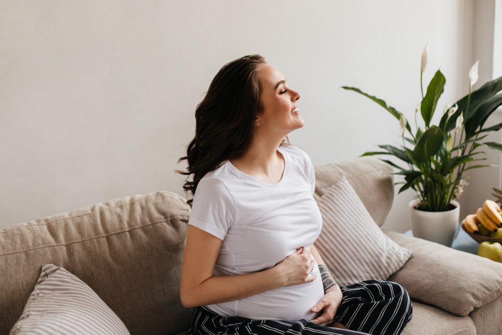 Entre melodías y emociones: ¿cómo influyen la música y la ansiedad materna en el bebé? 2 pretty brunette curly pregnant woman striped pants white tee smiles