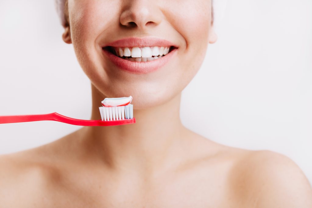 girl with sincere smile makes morning routine brushes her teeth isolated wall