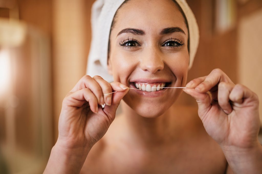 beautiful woman using dental floss cleaning her teeth bathroom